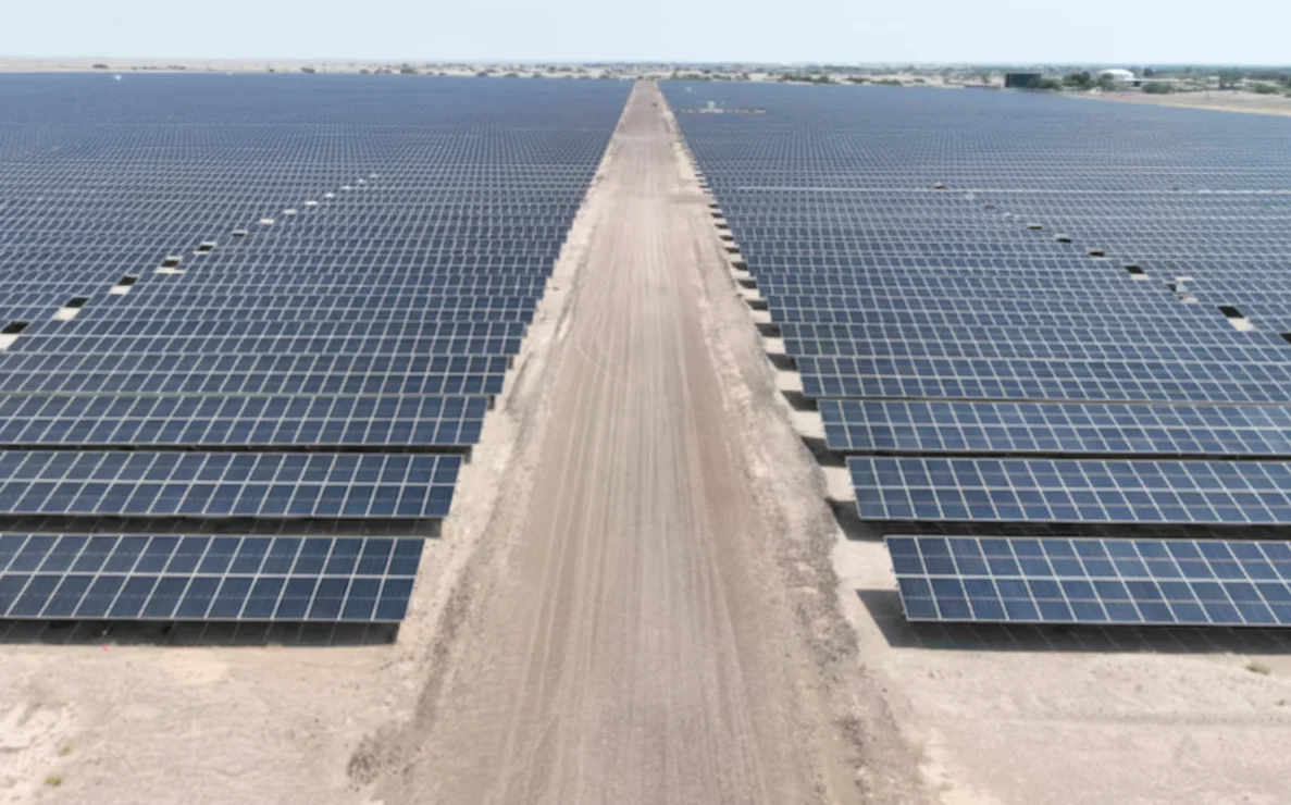 Vista aérea de la planta solar de Adén con cientos de paneles fotovoltaicos alineados en el desierto y un camino central de tierra