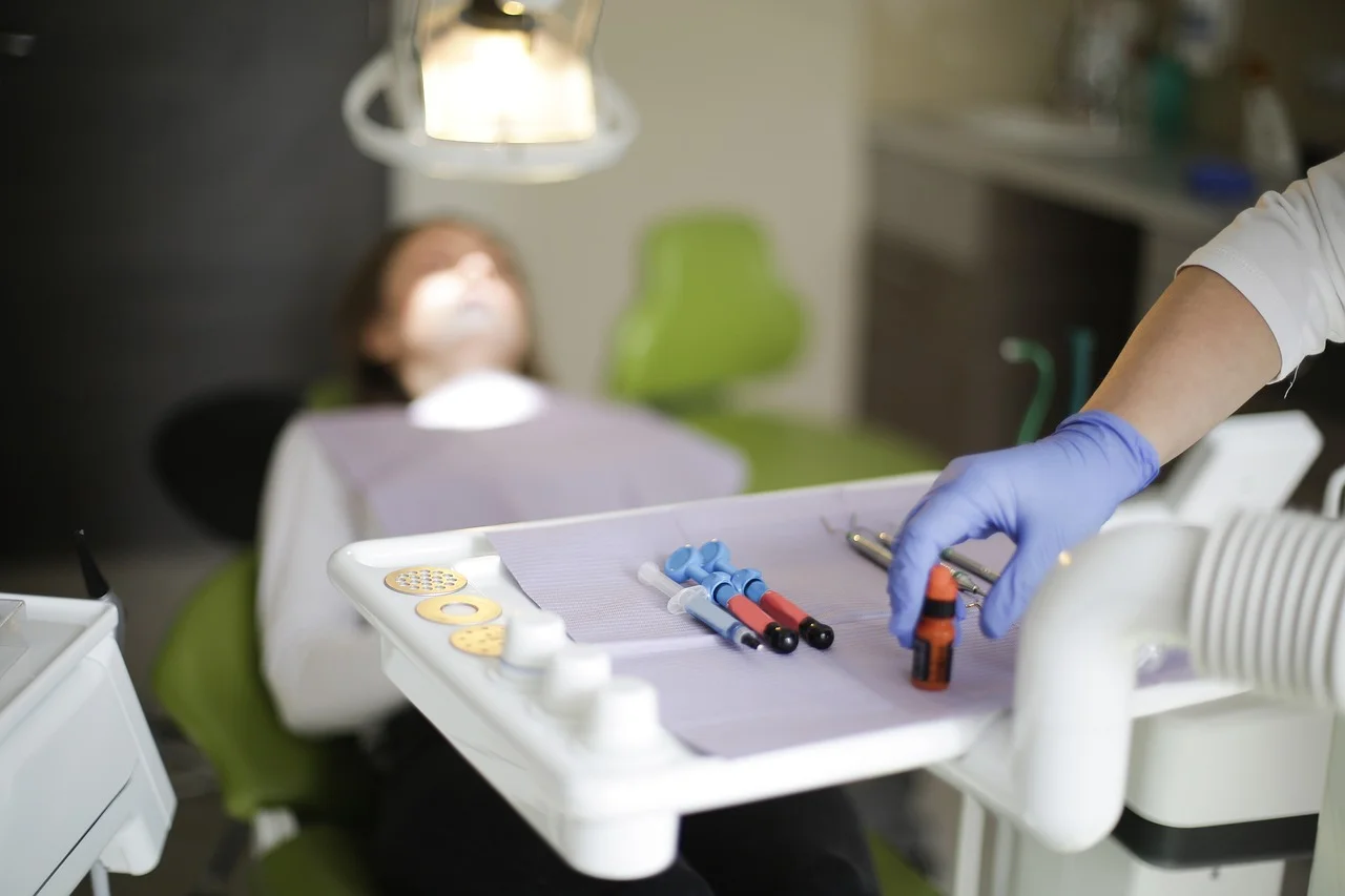 Dentista prepara instrumental médico mientras un paciente espera en el sillón