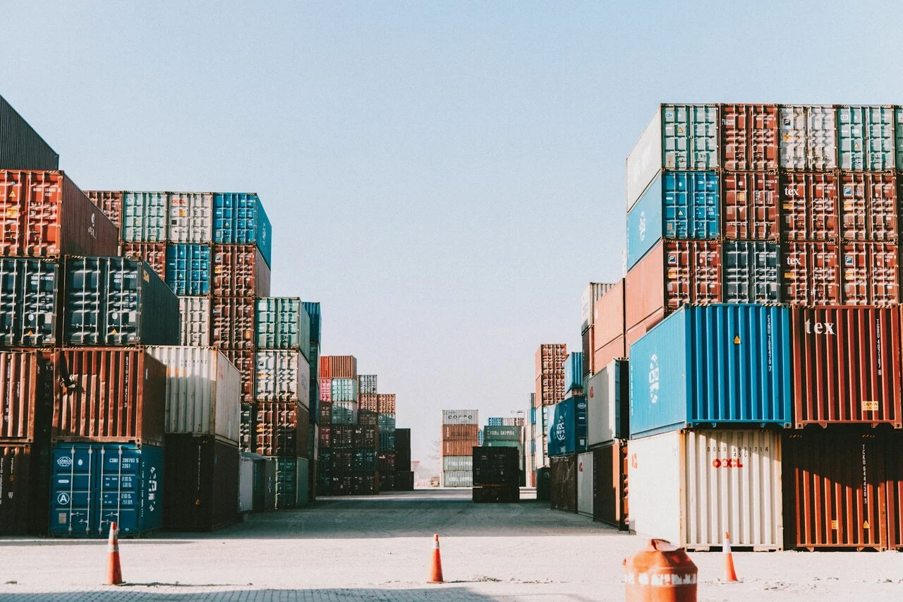 Filas de contenedores apilados en un puerto o zona industrial bajo un cielo despejado