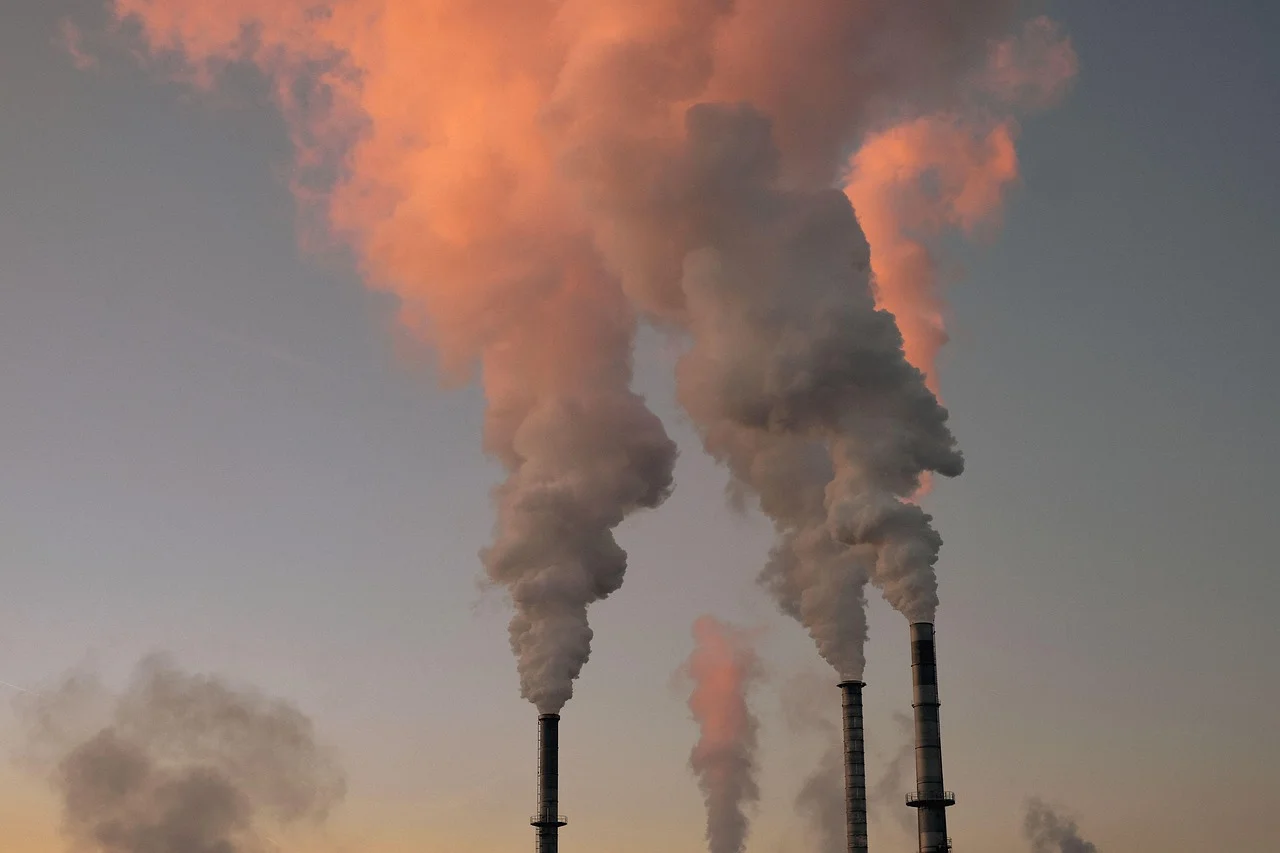 Chimeneas industriales emitiendo columnas de humo al atardecer