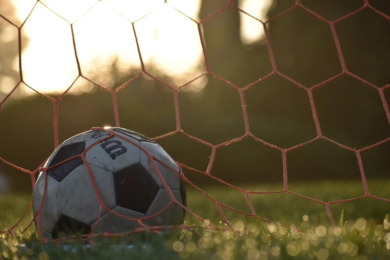 Balón de fútbol atrapado en la red de una portería al atardecer