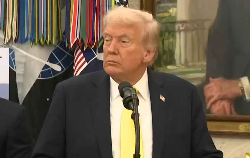 Donald Trump en una sala oficial, con banderas al fondo