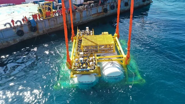 Plataforma amarilla con tanques blancos sumergiéndose desde un buque para pruebas de centro de datos submarino