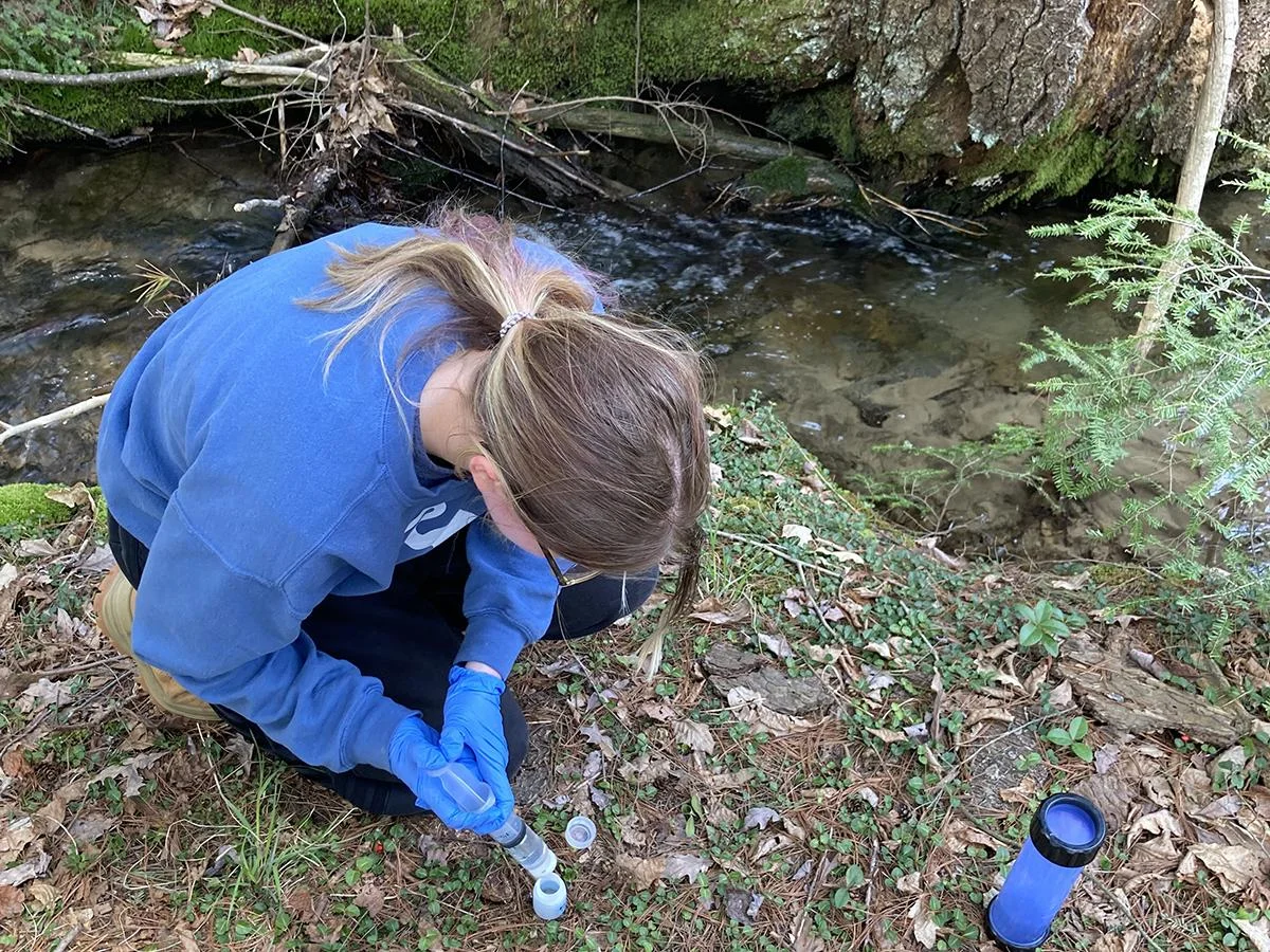 Estudiante de geociencias tomando muestras de agua en un pozo del Bosque Nacional Allegheny