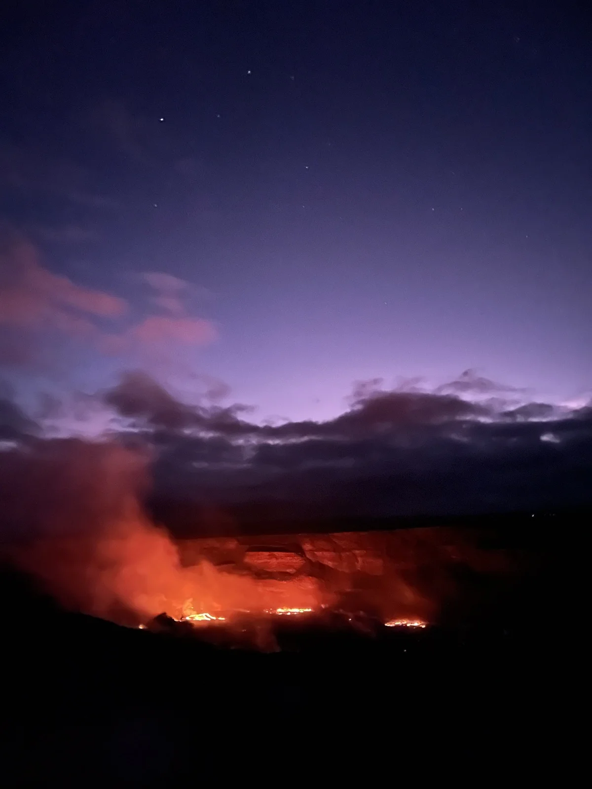 Cráter del Kīlauea emitiendo un resplandor rojizo que ilumina el paisaje nocturno.