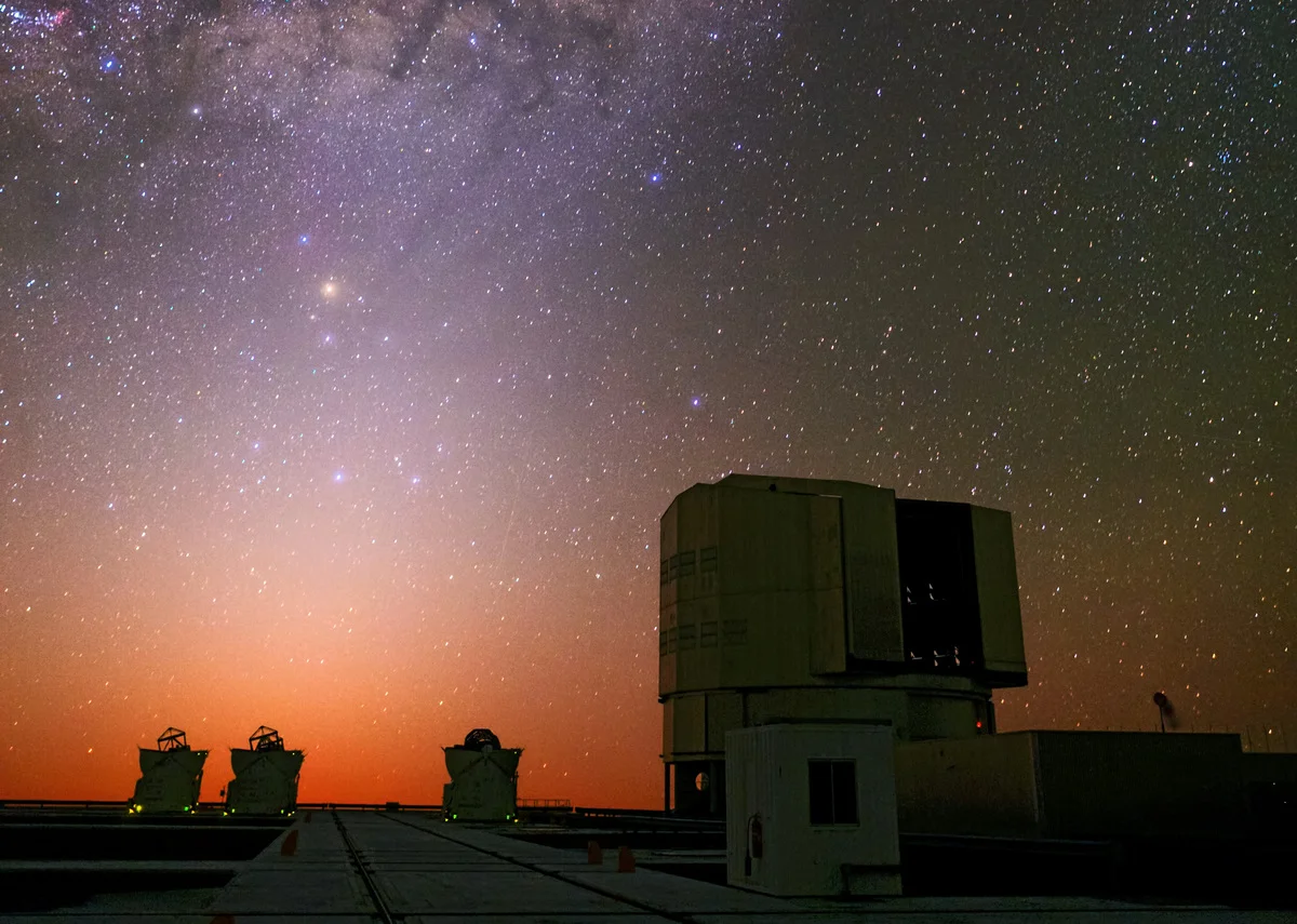Tres telescopios auxiliares del VLT iluminados por el resplandor anaranjado del anochecer