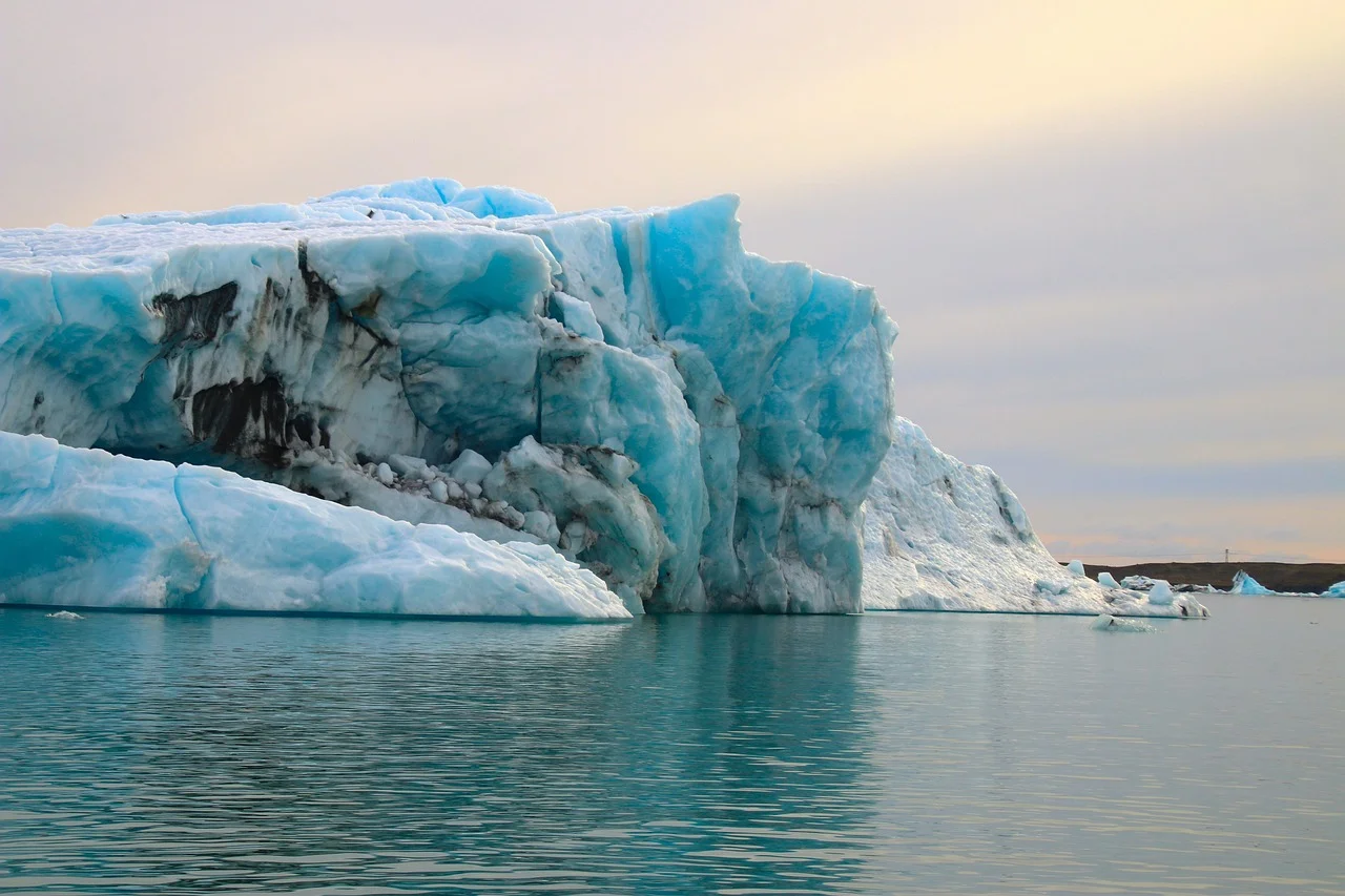 Gran iceberg azul con grietas oscuras flotando en aguas tranquilas