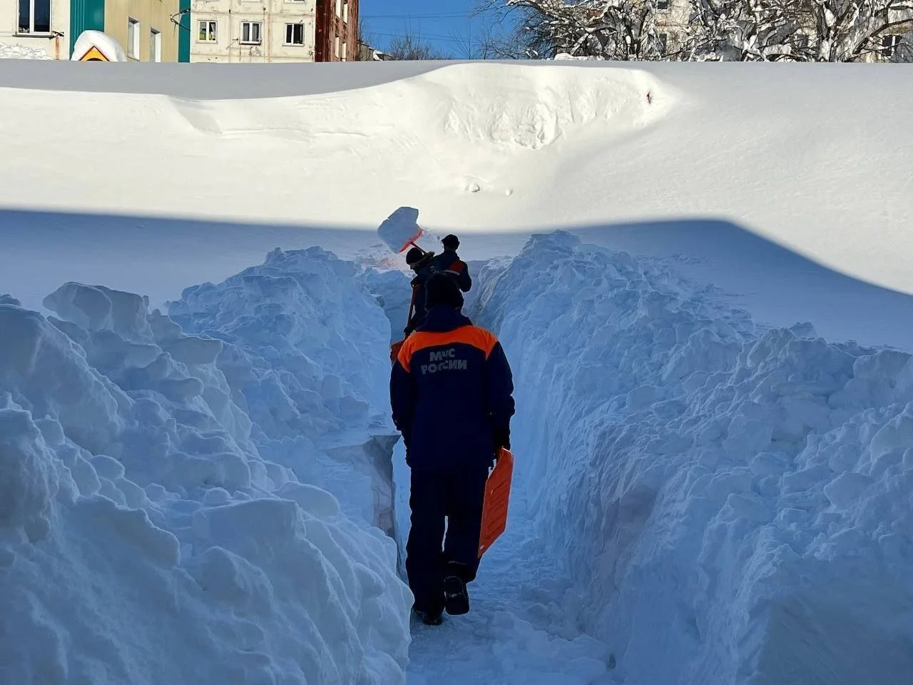 Persona caminando por un pasillo abierto entre muros de nieve acumulada en una ciudad de Kamchatka