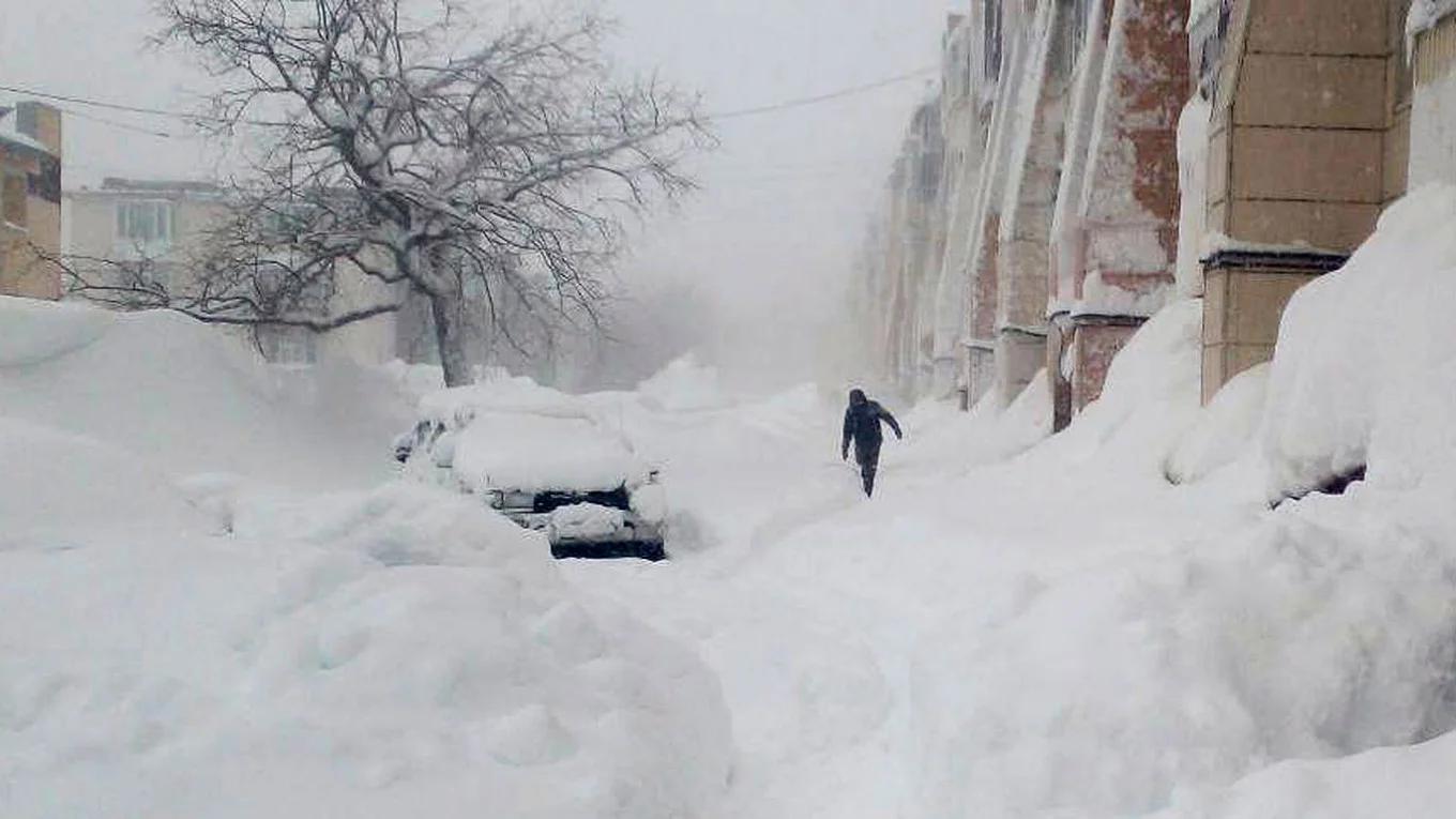 Coches parcialmente enterrados por la nieve junto a un edificio residencial
