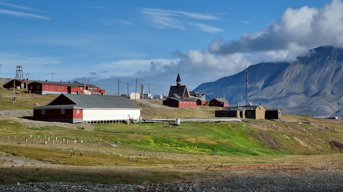 Terreno con vegetación junto a antiguos edificios agrícolas en Longyearbyen
