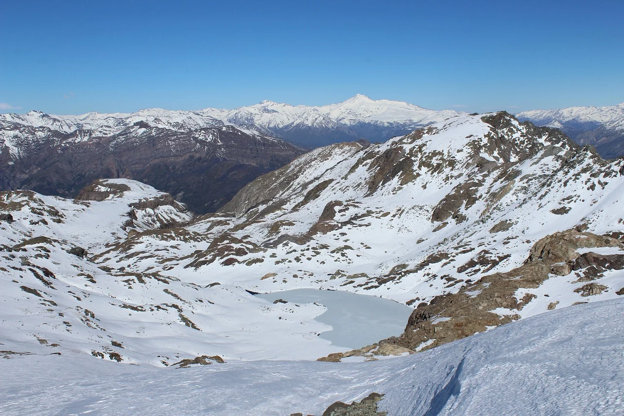 Cordillera de los Andes nevada con lago de montaña en primer plano