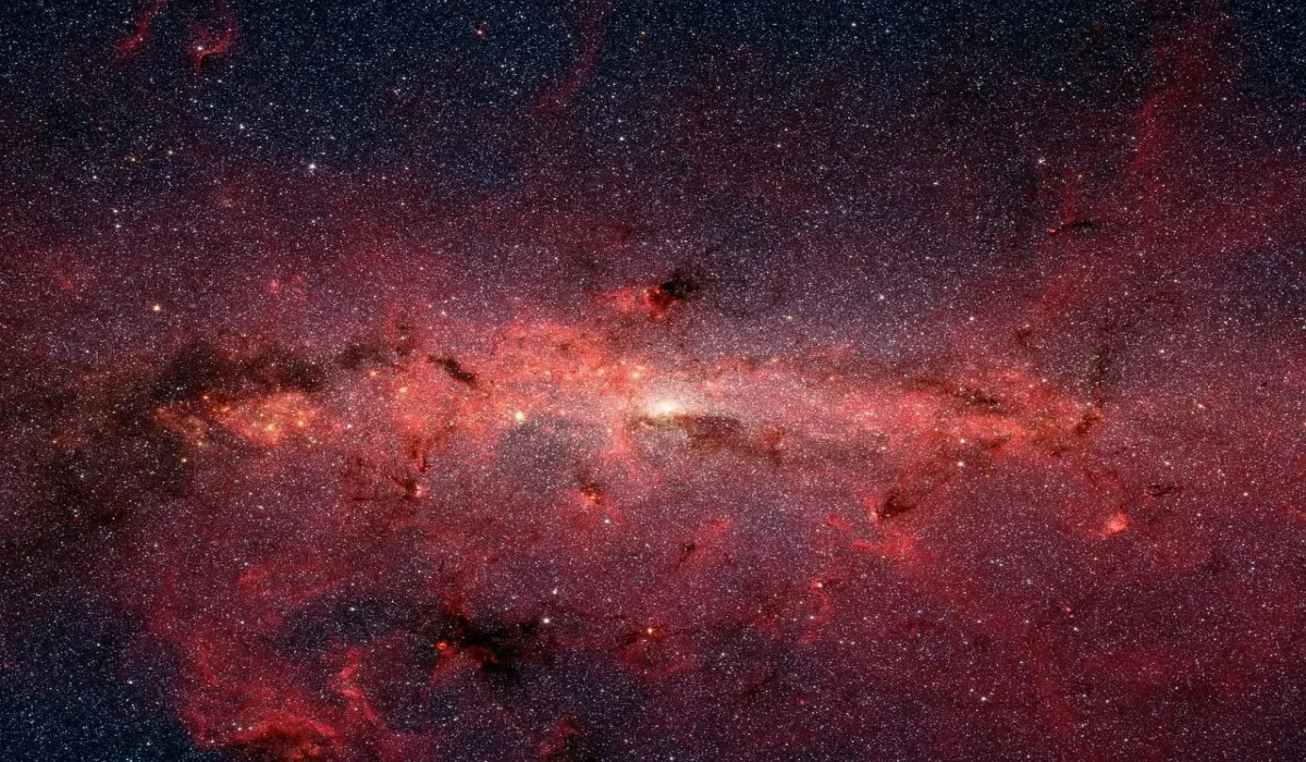Imagen infrarroja de la Vía Láctea con tonos rojizos y una gran concentración de estrellas.