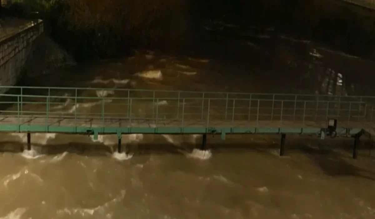 Imagen del río Manzanares en Madrid con un caudal desbordado, cubriendo parcialmente una pasarela peatonal