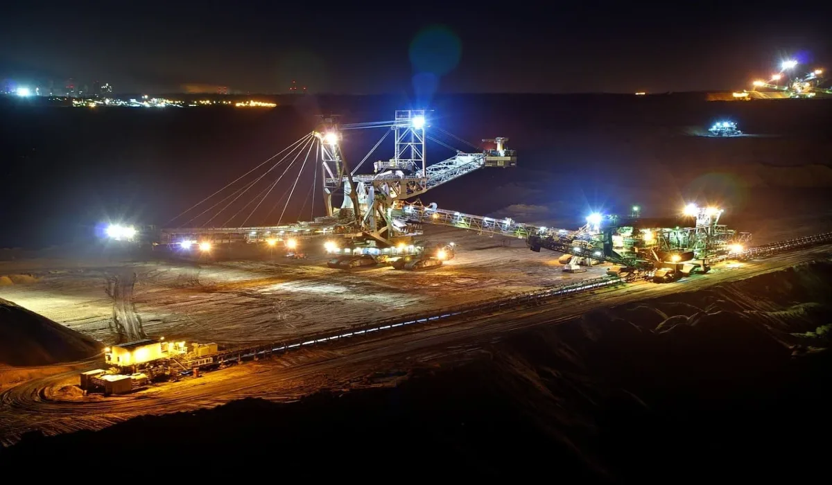 Excavadora minera iluminada operando de noche en una mina a cielo abierto.