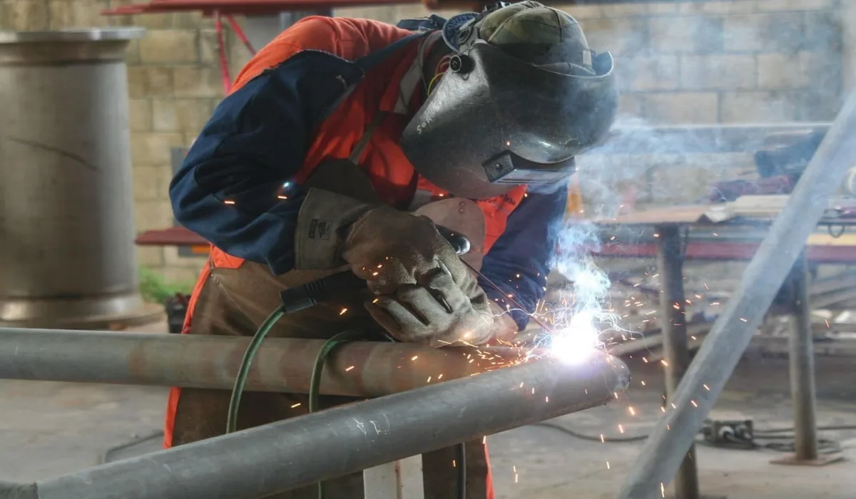 Trabajador soldando una estructura metálica con equipo de protección