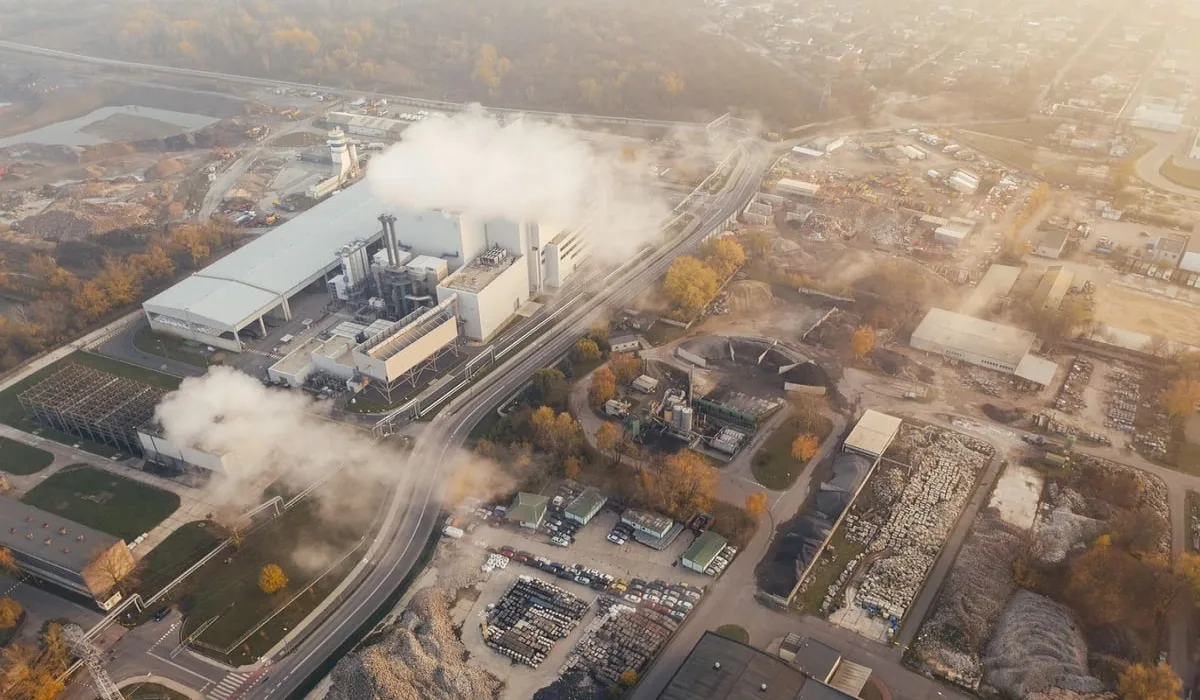 Vista aérea de una planta industrial emitiendo contaminantes en un área urbana