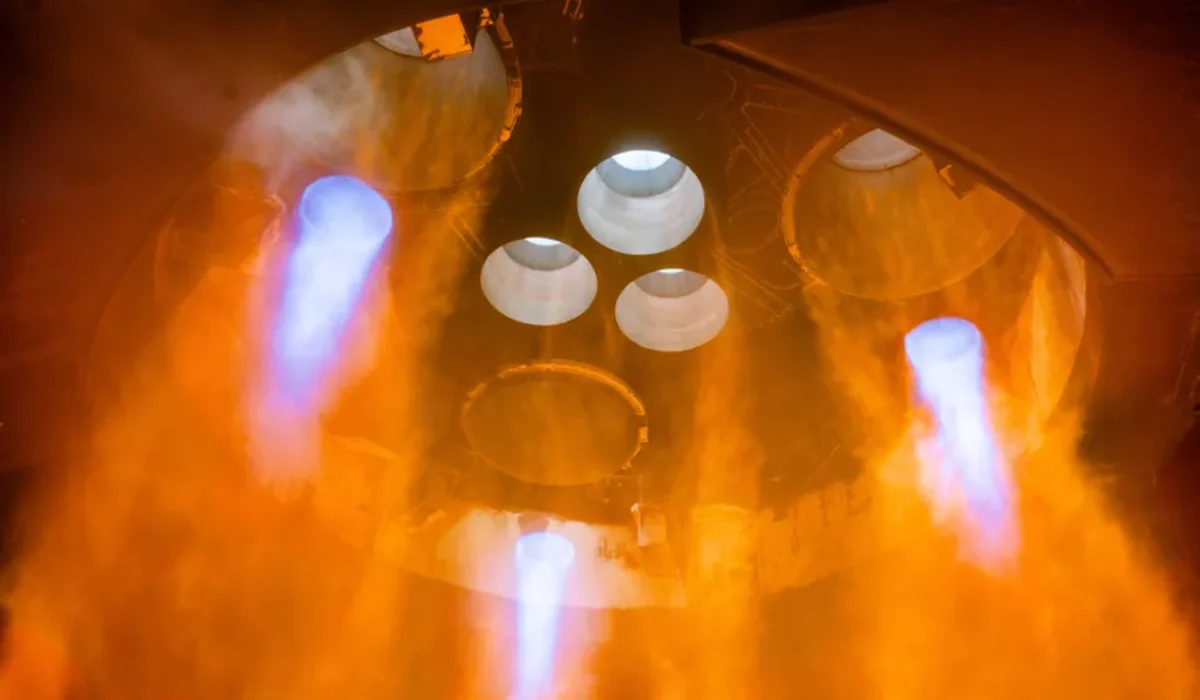Motores Raptor de la etapa superior de Starship encendidos con llamas naranjas y azules en un banco de pruebas