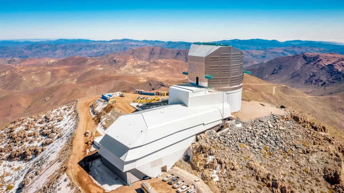 Vista aérea del Observatorio Vera C. Rubin, ubicado en la cima de una montaña rocosa en Chile, rodeado por un paisaje árido y montañoso.