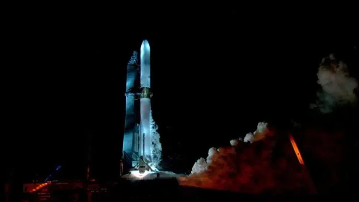 Un cohete New Glenn de Blue Origin en posición vertical, iluminado mientras se prepara para su lanzamiento en un entorno oscuro.
