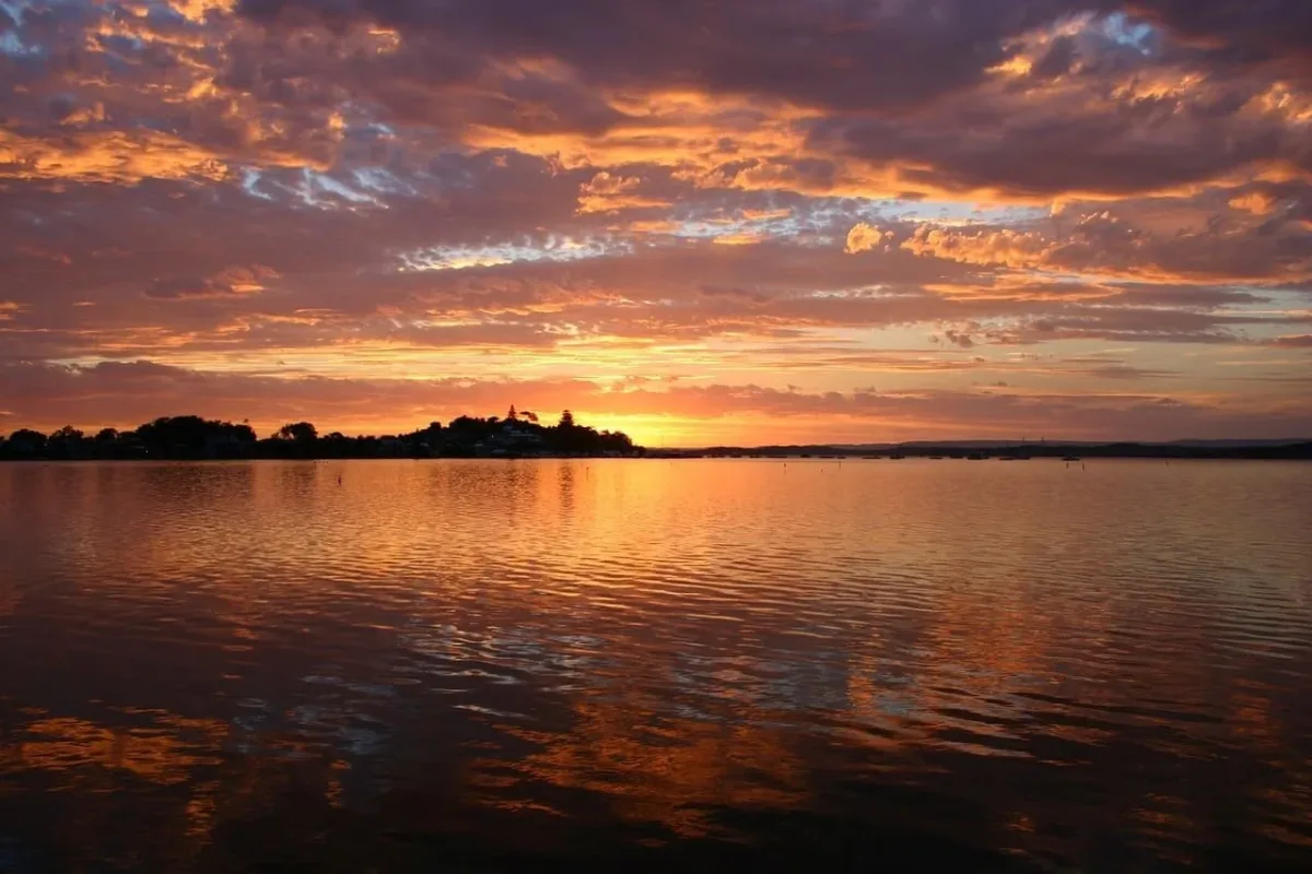 Hermoso atardecer sobre un lago tranquilo, con cielos dramáticos reflejándose en el agua.