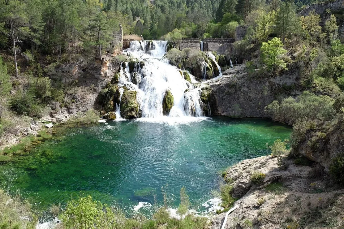 Impresionante cascada en un entorno natural con aguas cristalinas y vegetación exuberante.