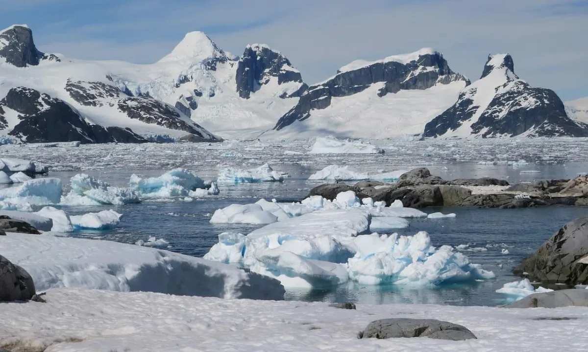 Montañas nevadas y bloques de hielo flotando en aguas antárticas tranquilas