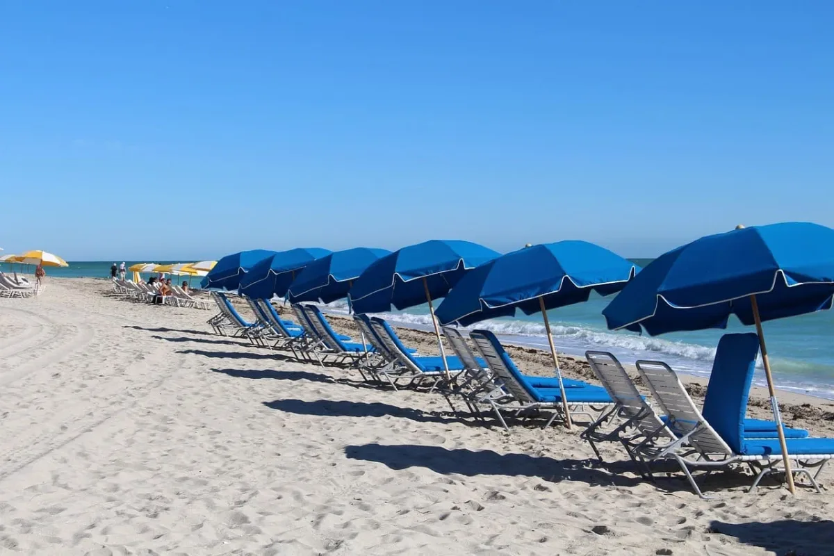 Playa de Miami-Dade con sombrillas vacías bajo el sol intenso, en medio de la advertencia de bandera roja por condiciones propicias para incendios