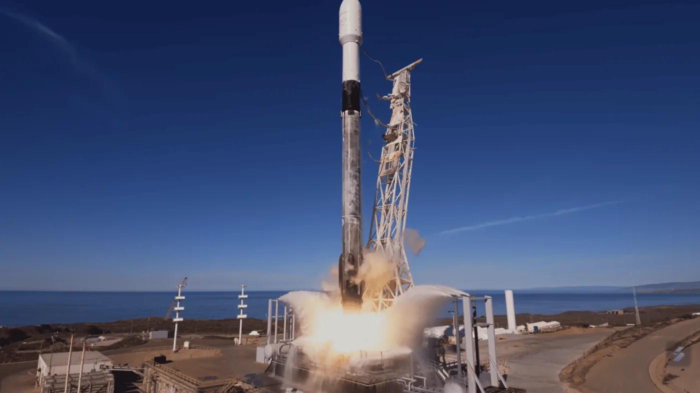 Lanzamiento del Falcon 9 de SpaceX en una misión nocturna, con un potente resplandor iluminando la plataforma de despegue.
