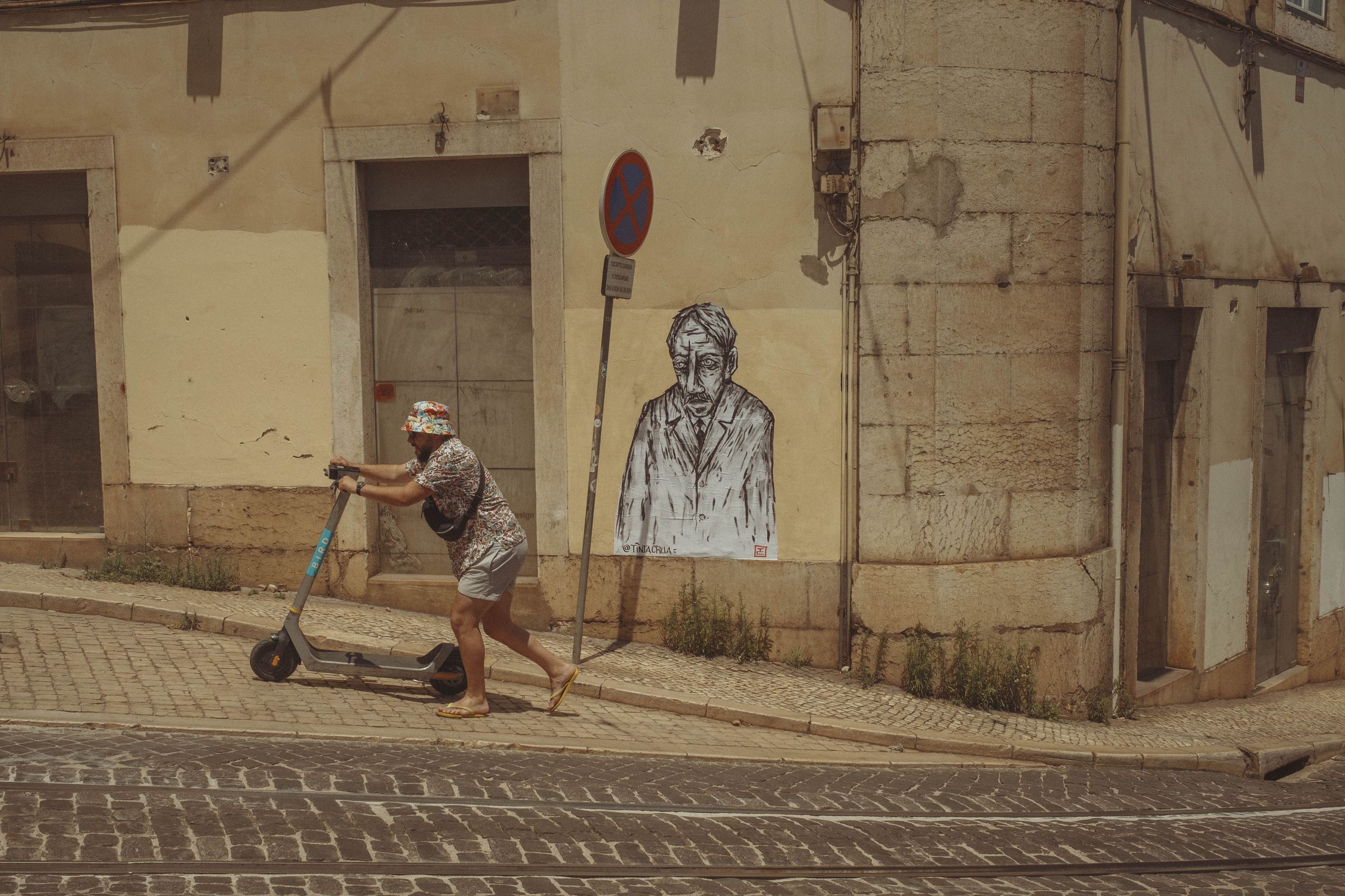 A tourist in a bucket hat and patterned outfit rides an electric scooter past a crumbling corner building with street art depicting a melancholic figure looking at him disappointingly. The worn yellow facade shows peeling plaster and weeds growing from cracks, while harsh shadows slice across the cobblestone street in the afternoon sun.