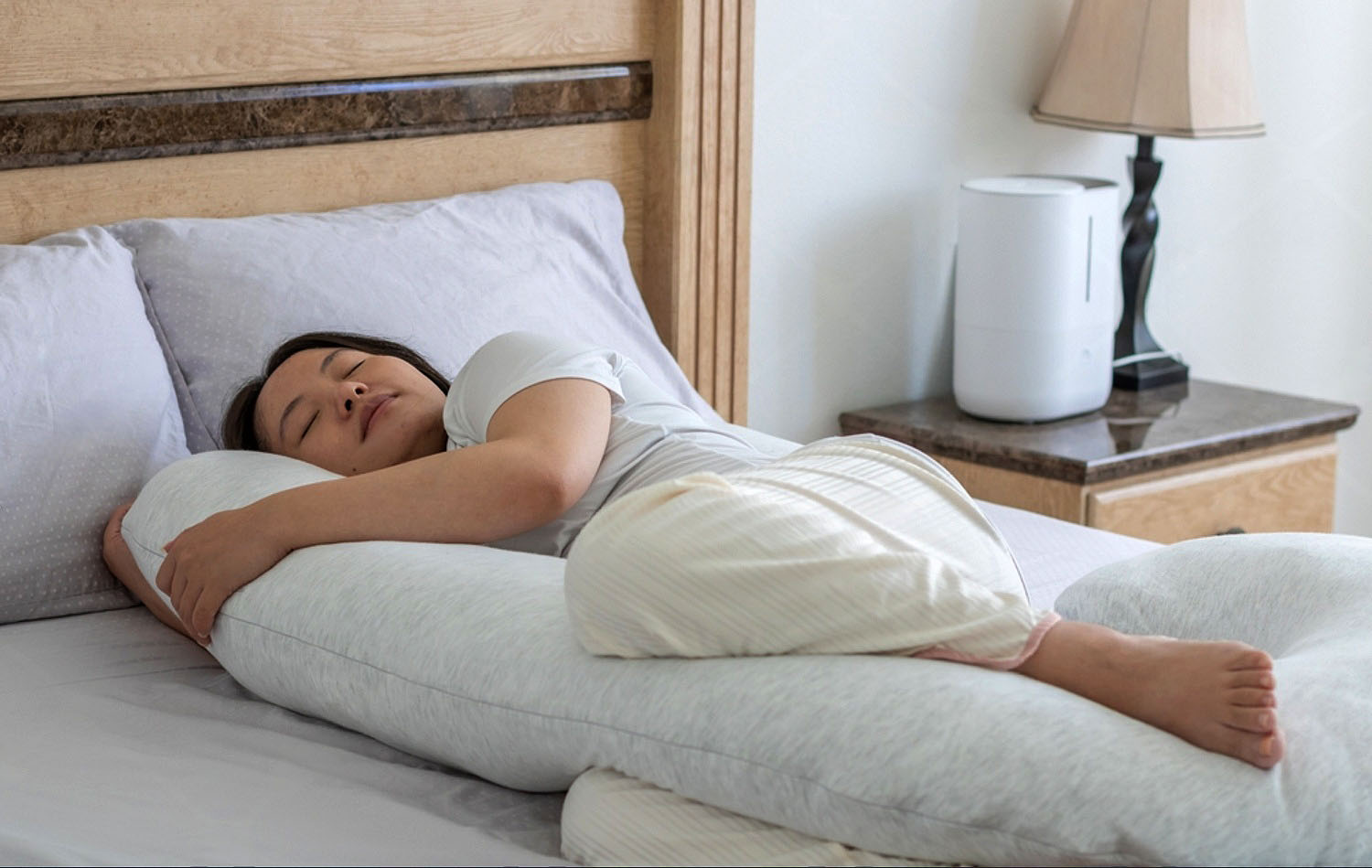 A pregnant woman sleeping on her side with a full-body pregnancy pillow