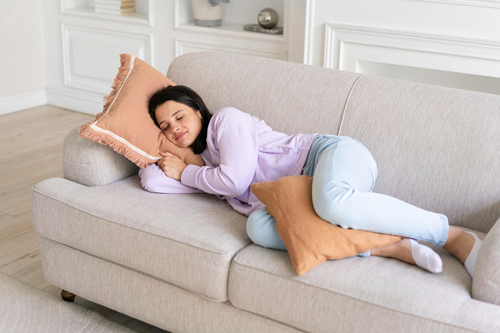 A women sleeping with a pillow between their legs on a couch.