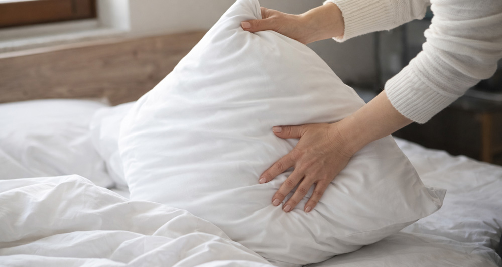 A hand fluffing a pillow