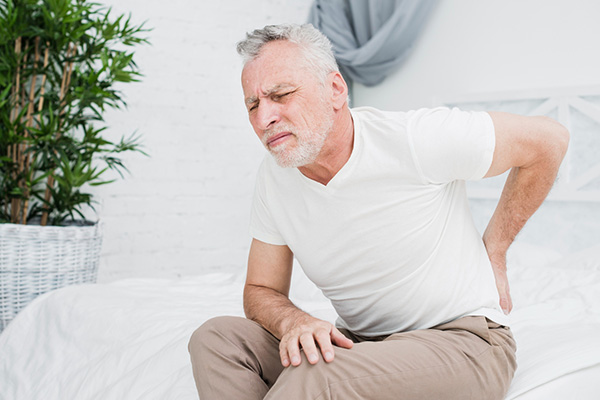 A man sitting in pain with his hand on his lower back
