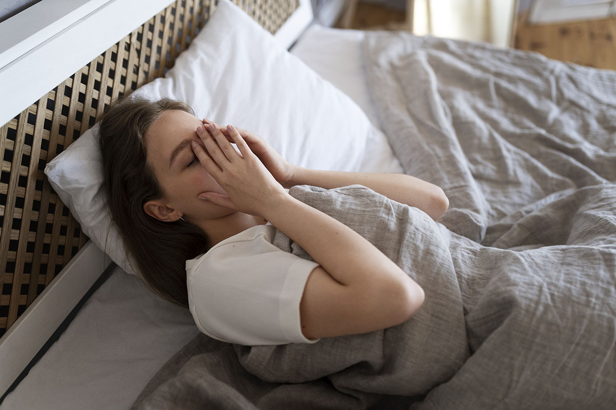 A woman in bed, unable to sleep, experiencing sleep deprivation