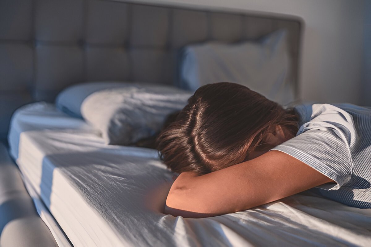 A woman lying on her stomach on a bed, unable to wake