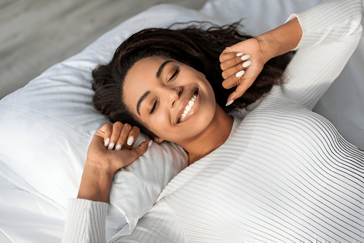 A woman waking up with a smile on her face, seemingly after experiencing a good night’s sleep