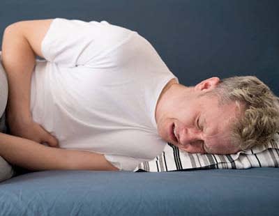 A man agonizing in pain while sleeping due to a urinary tract infection