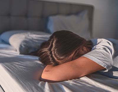 A woman lying on her stomach on a bed, unable to wake