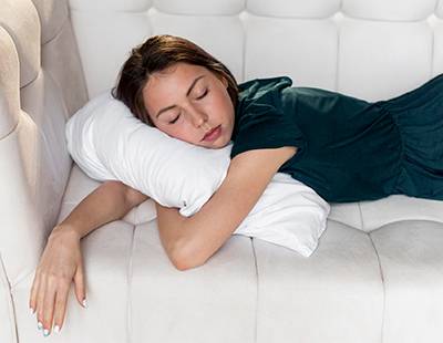 A woman sleeping on her side with her arms wrapped around a pillow.
