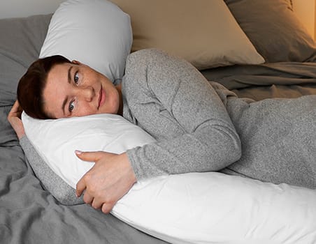 A woman using a body pillow.