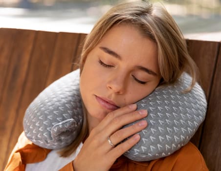 A woman sleeping upright while using a travel neck pillow.