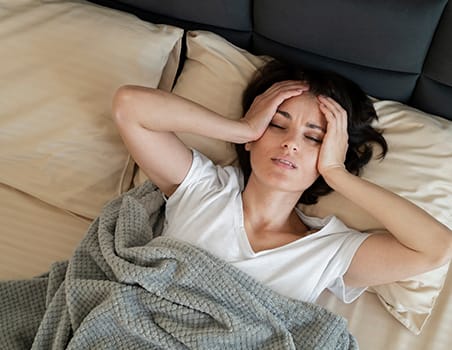 A woman seemingly suffering from a headache due to lack of proper sleep.