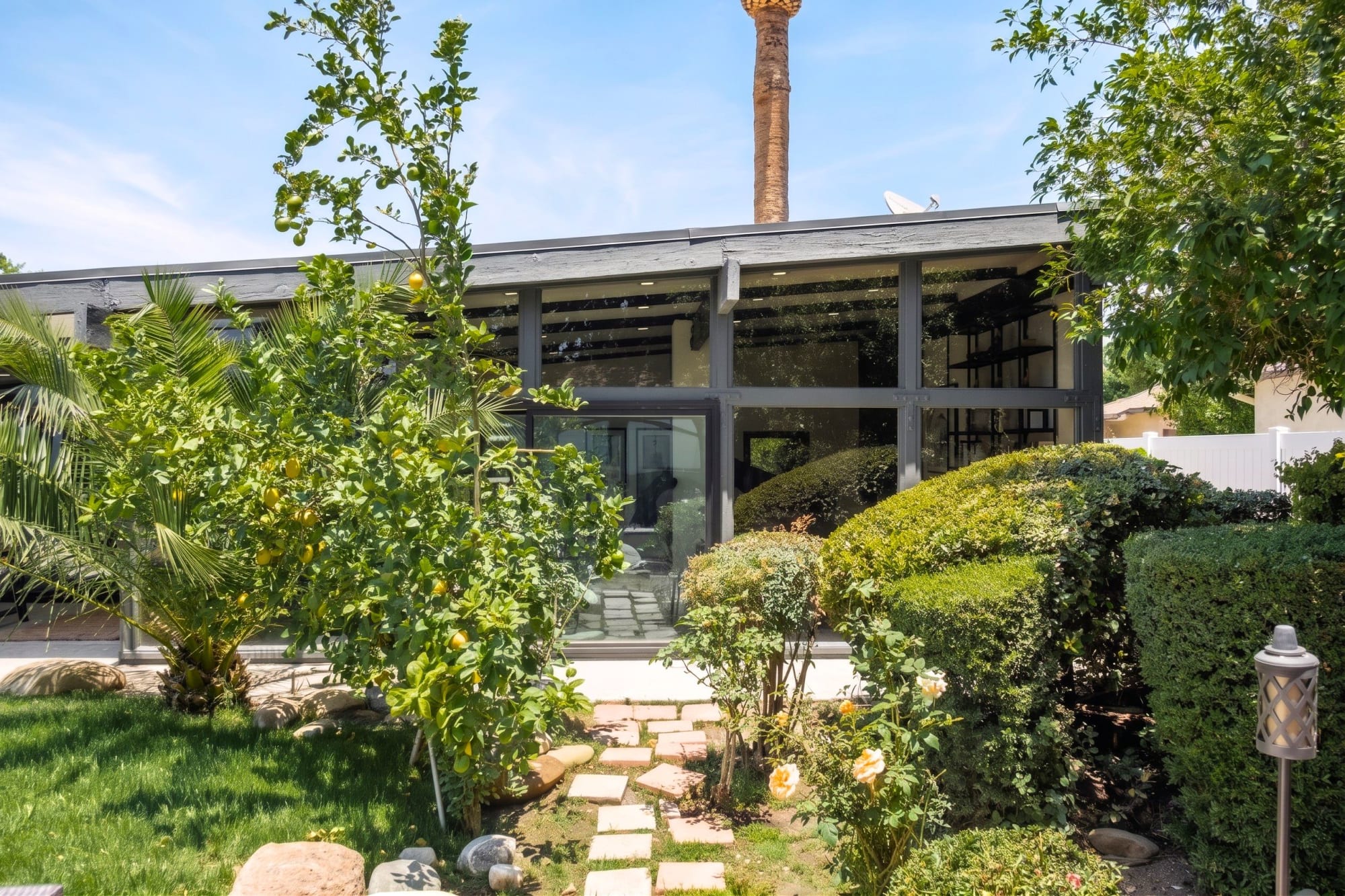 The glass-wall living room, floor-to-ceiling sliders dissolving the boundary between inside and garden.