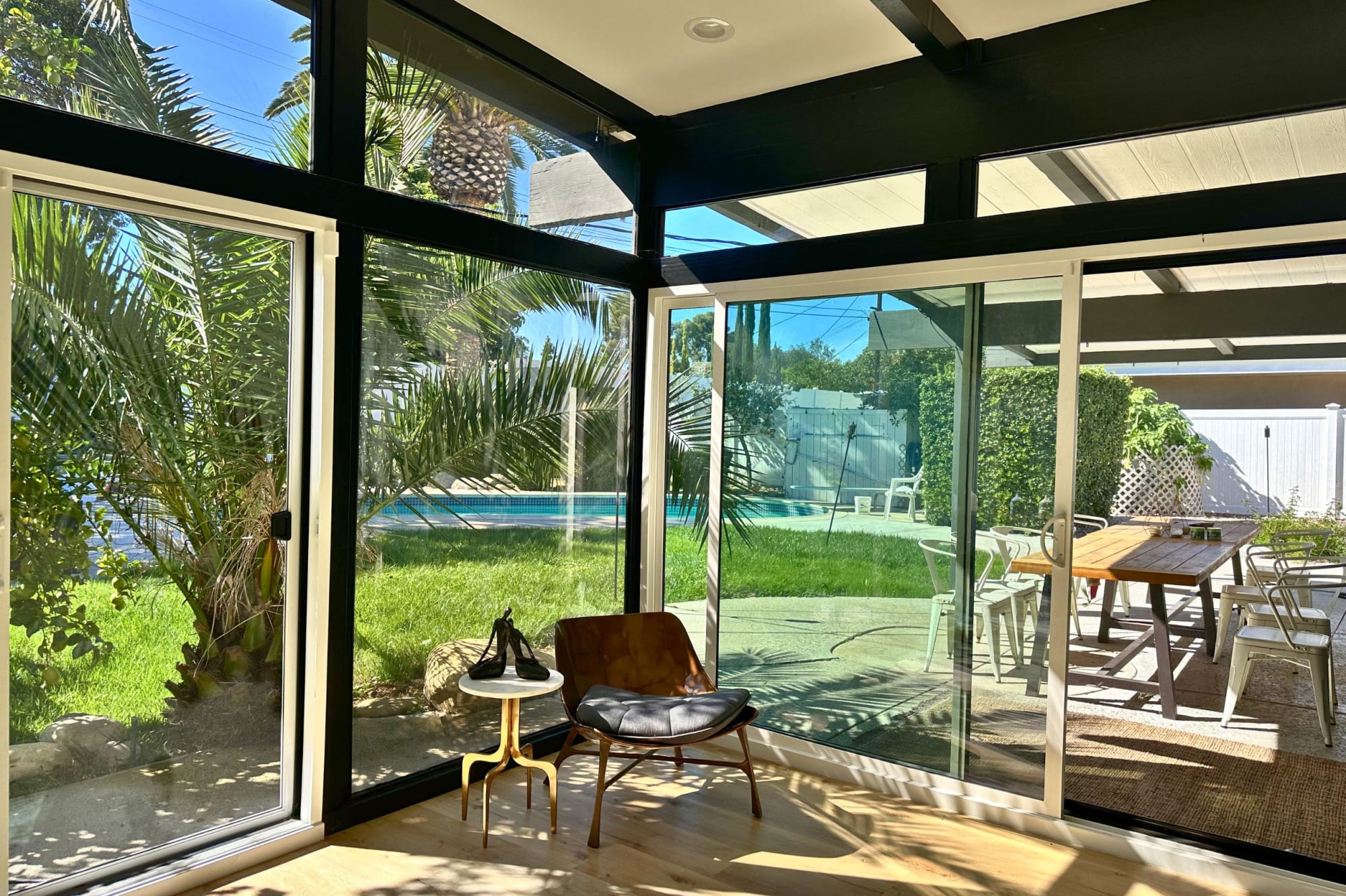 View from the living room out to the backyard, glass dissolving the boundary between inside and out.