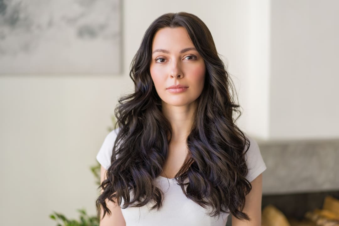 Rhinoplasty: Woman with long dark hair and balanced facial features indoors