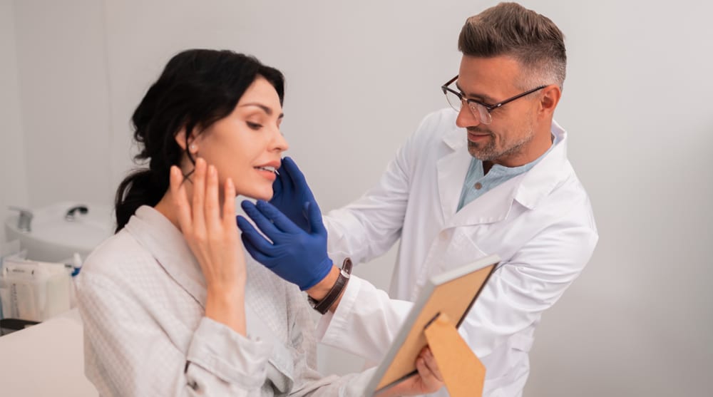 Female patient consulting with facial plastic surgeon during deep plane facelift evaluation in medical clinic setting