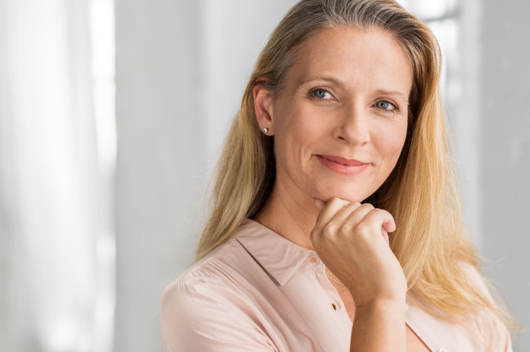 Mohs surgery: Mature woman with long blonde hair resting her hand under her chin
