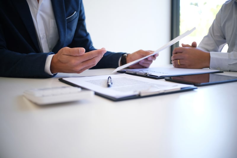 a view of two business-suit clad people's hands gesticulating above a table with tablets in a business setting