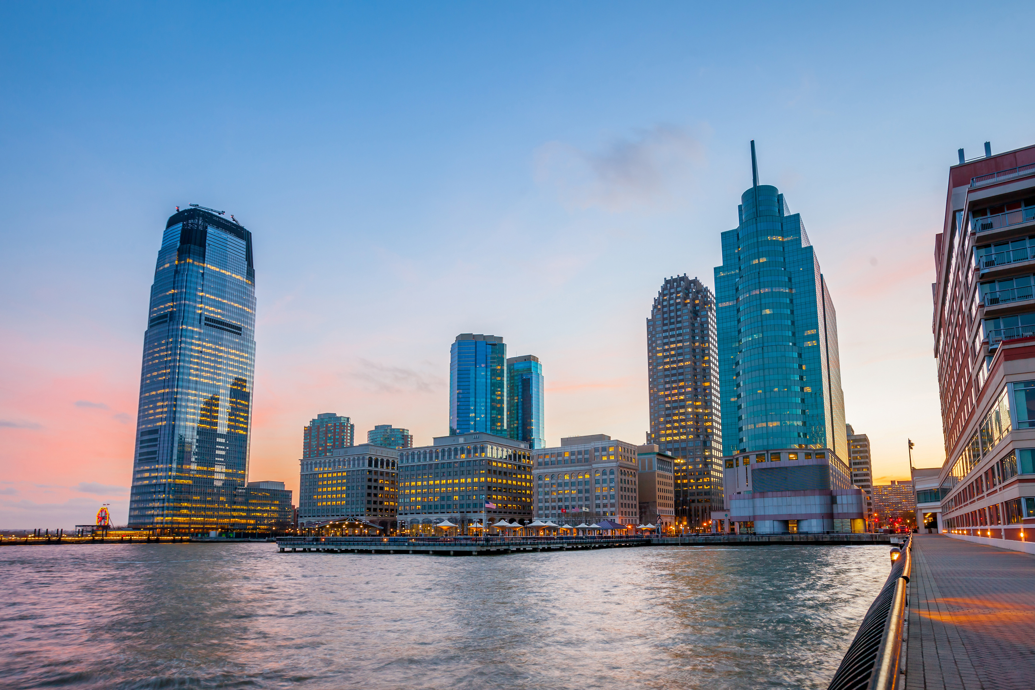 New York waterfront with several tall, lit office buildings at dusk