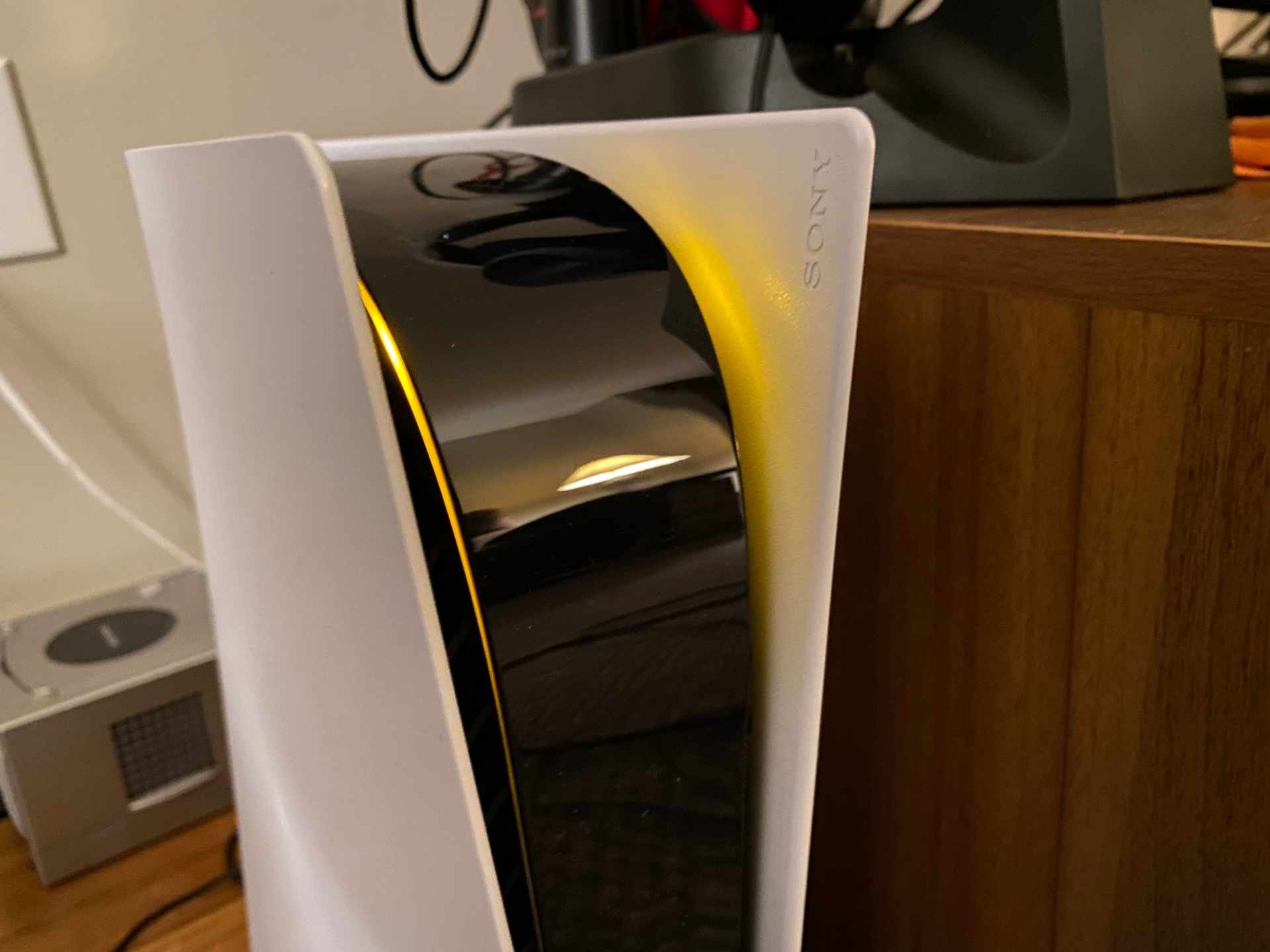 A PlayStation 5 in rest mode showing the amber standby light on the front of the console